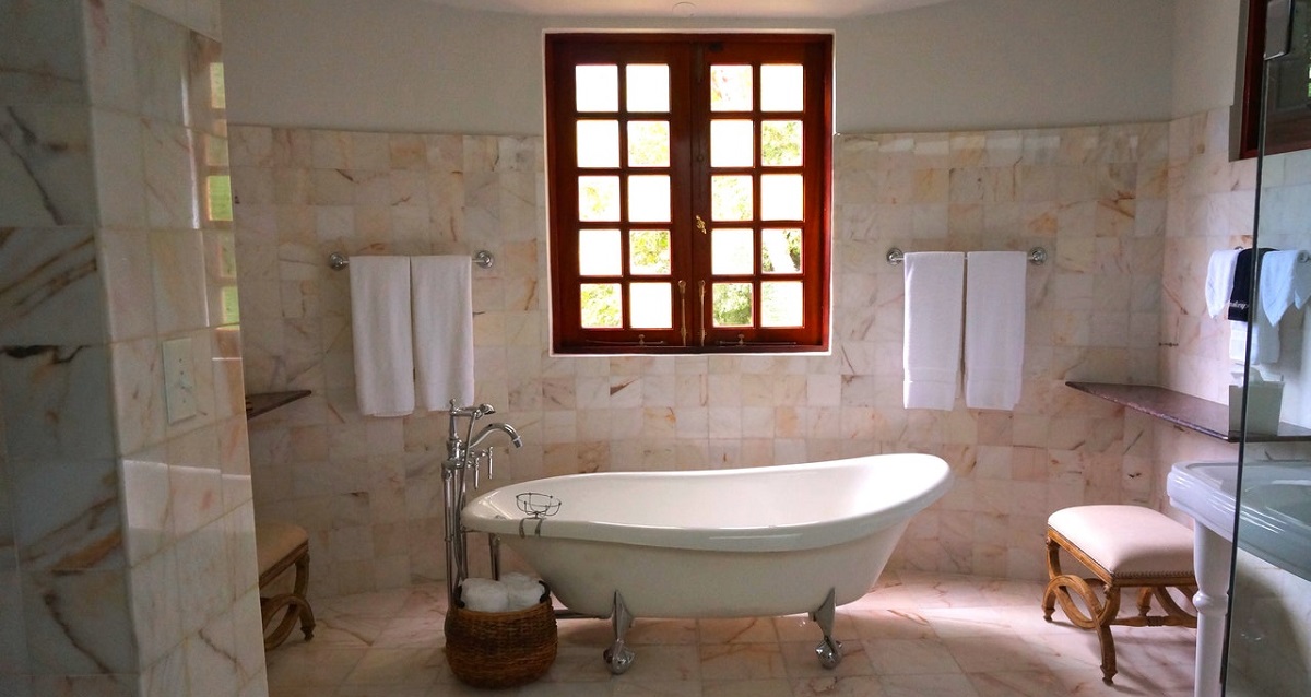 a stylish bathroom showinga free standing bath and a garden scene though the window