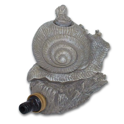 A garden sprinkler in the shape of a snail sitting on a rock.