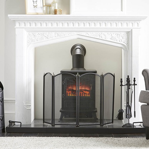 Fireplace starter set showing a black spark guard and companion set arranged in front of a stove fire